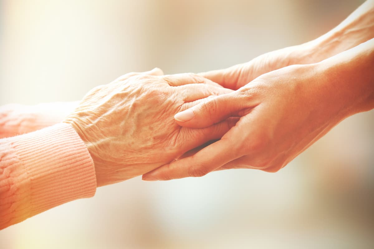 Caregiver holding client's hand with warmth and care